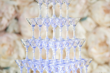 Pyramid from glasses of champagne on wedding party. Floral background