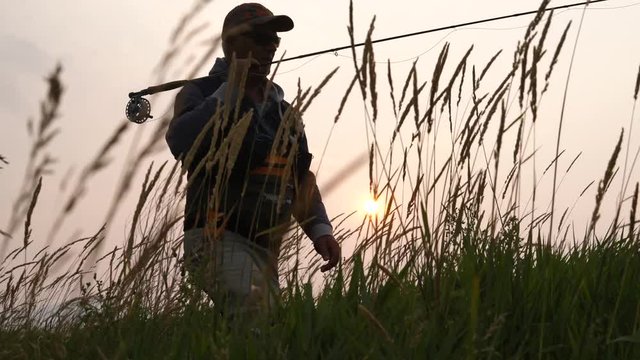 Fly-fisherman at sunset in country field