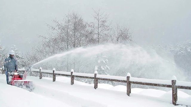 Snow blower removes snow from road in the park.