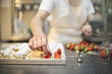 Pastry chef making pastries with cream and fruits