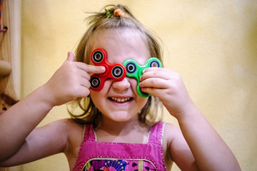 Cute little girl holds two fidget spinners on her face