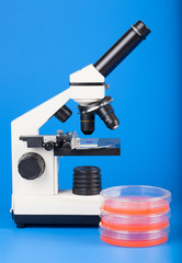 Scientific microscope and petri dishes for scientific research on blue background