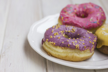 Fresh donuts in the white plate on wooden background