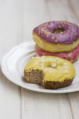 Fresh donuts in the white plate on wooden background