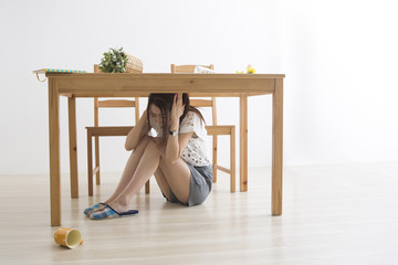 地震でテーブル下に避難する女性