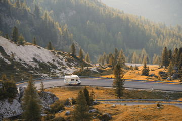 Caravan car travels on a mountain road at sunset