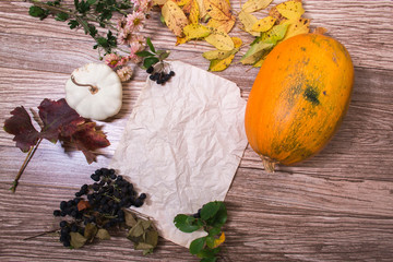 Autumn still life: pumpkin and autumn leaves on a wooden background.