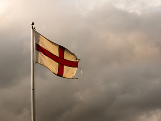 England flag flying in the sky on a pole, dramatic overcast