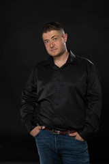 Young confident man portrait of a confident businessman showing by hands on a black background. Ideal for banners, registration forms, presentation, landings, presenting concept.