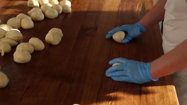 Dough on table. Knead the dough. At the bakery, preparing dough to be made buns, bread factory. Confectioners bake pies. Confectioners make desserts. Bakers cook buns for baking. Handmade making buns.