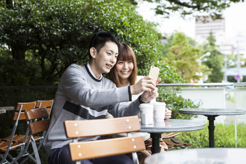 A young couple trying to take pictures on the cafe terrace