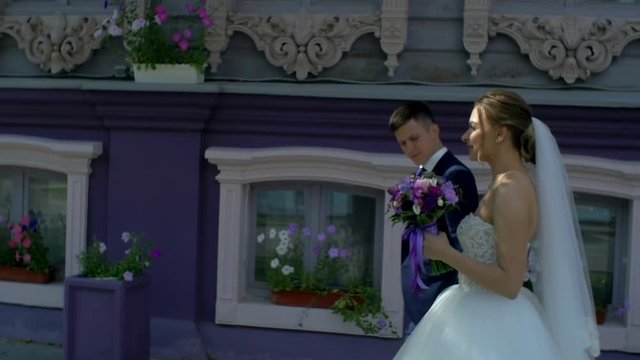 Newlyweds walking along the street past the building slow motion