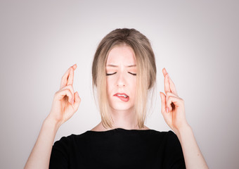 Junge Frau kreuzt Finger hoffnungsvoll