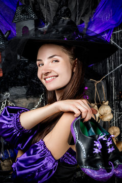 Portrait of a happy witch in a suit with shoes on a black background