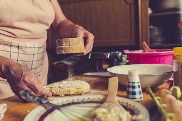 Close up of senior female baker hands kneading dough in kitchen.