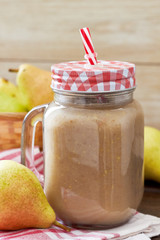 Pear smoothie served in mason jar on wooden background