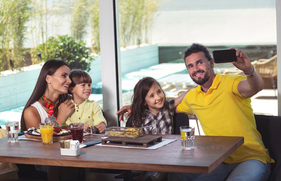 A four-member family having great time in a restaurant, make selfie photo