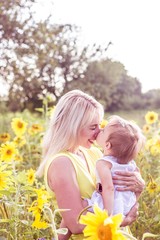 Family is walking along the summer flowering field. Happy mother and daughter in the sun. Summer. Sunflowers.