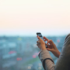 Closeup of hands holding smartphone with city below
