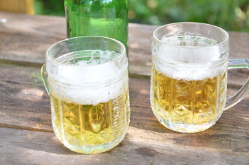 Two Glasses of cider or light beer and bottle on rustic wooden background octobcrfest