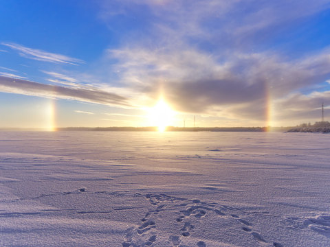 Beautiful halo around setting sun caused by small ice crystals in the air. Winter background.