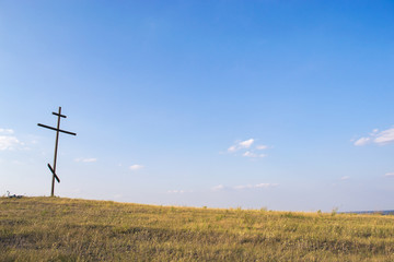 A large wooden cross on the mountain. September landscape.