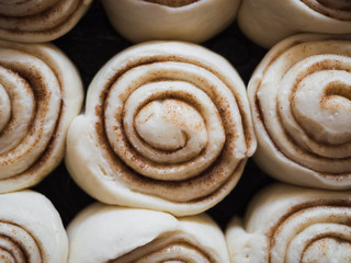 Cinnamon rolls made of fresh yeast dough while rising and waiting to go in the oven, top view 