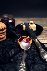 Spoon with jam near chocolate cookies and biscuits on black table background. Afternoon break time. Breakfast.