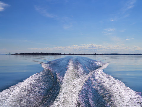 Wake behind fast moving motor boat on calm sea.