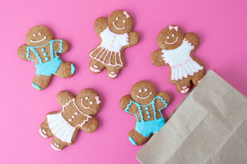 Homemade gingerbread man on pink background. Boys and girls were pouring out of the package. Concept of gift. Picture for a confectionery catalog. Invitation or greeting card with copy space. Isolated