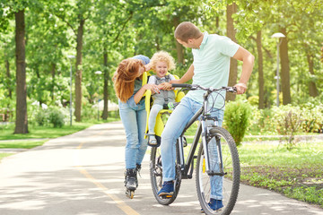Shot of happy parents cuddling with their baby while cycling and rollerblading together at the park love family affection parenting childhood emotions active lifestyle.