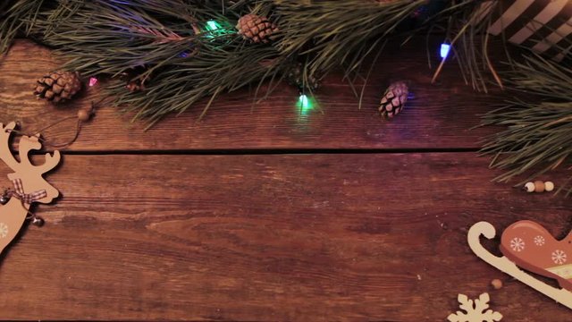 Festive Christmas wooden background. Table with New year decoration and Xmas tree with blinking lights on backdrop loop video. Winter holiday advertising concept