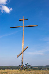 Mountain biking near a large wooden cross on the mountain.