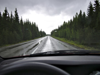 Driving countryside highway in heavy rain on wet slippery road. Windshield wipers in action, driver's view.