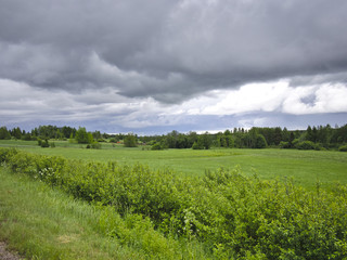 Fototapeta na wymiar Murky thunder clouds over green agricultural fields.