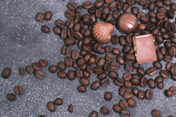 Coffee beans and tiles of dark chocolate on a dark matte background.