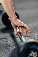 cropped view of sportsman training with barbell in gym