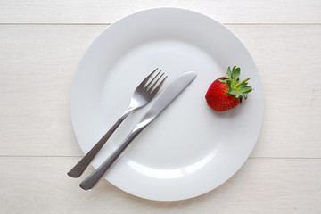 Red strawberry on blank plate, from overhead