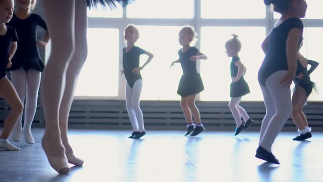 Little ballerinas learn to dance. Little girls learn to dance in black tutus. School of ballet. Feet closeup