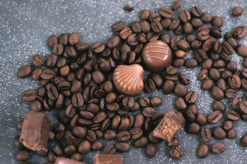 Coffee beans and tiles of dark chocolate on a dark matte background.