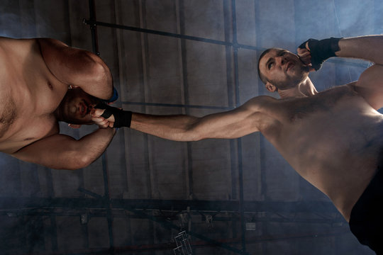 Two muscular men fighting, bodybuilders punching each other, training in martial arts, boxing, jiu jitsu