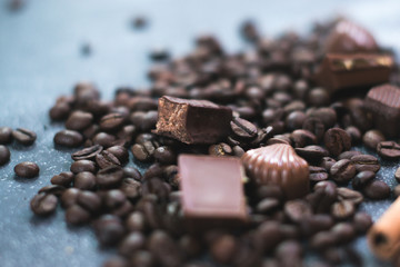 Coffee beans and tiles of dark chocolate on a dark matte background.