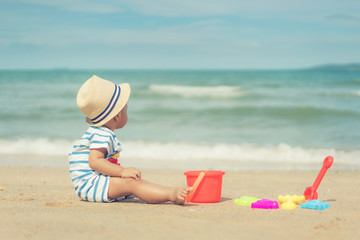 Asian 10 months baby boy playing on the sandy summer beach near the sea. Summer, Travel, Holiday concept.