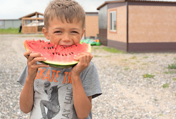 Happy boy eating a ripe watermelon.
