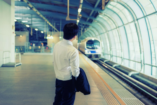 Asian young businessman waiting metro train at train station. Business travel concept.