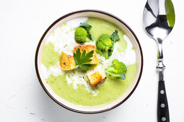 Green soup puree with broccoli on white table. Top view.