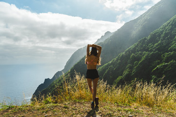Adventurer girl looking at Madeira volcano mountain range and ocean in the morning
