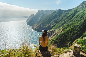 Girl overlooking Madeira volcano cliffs and hilly cliff shore - obrazy, fototapety, plakaty