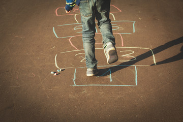 little boy playing hopscotch on playground