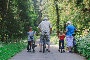 active senior couple with kids riding bikes in nature
